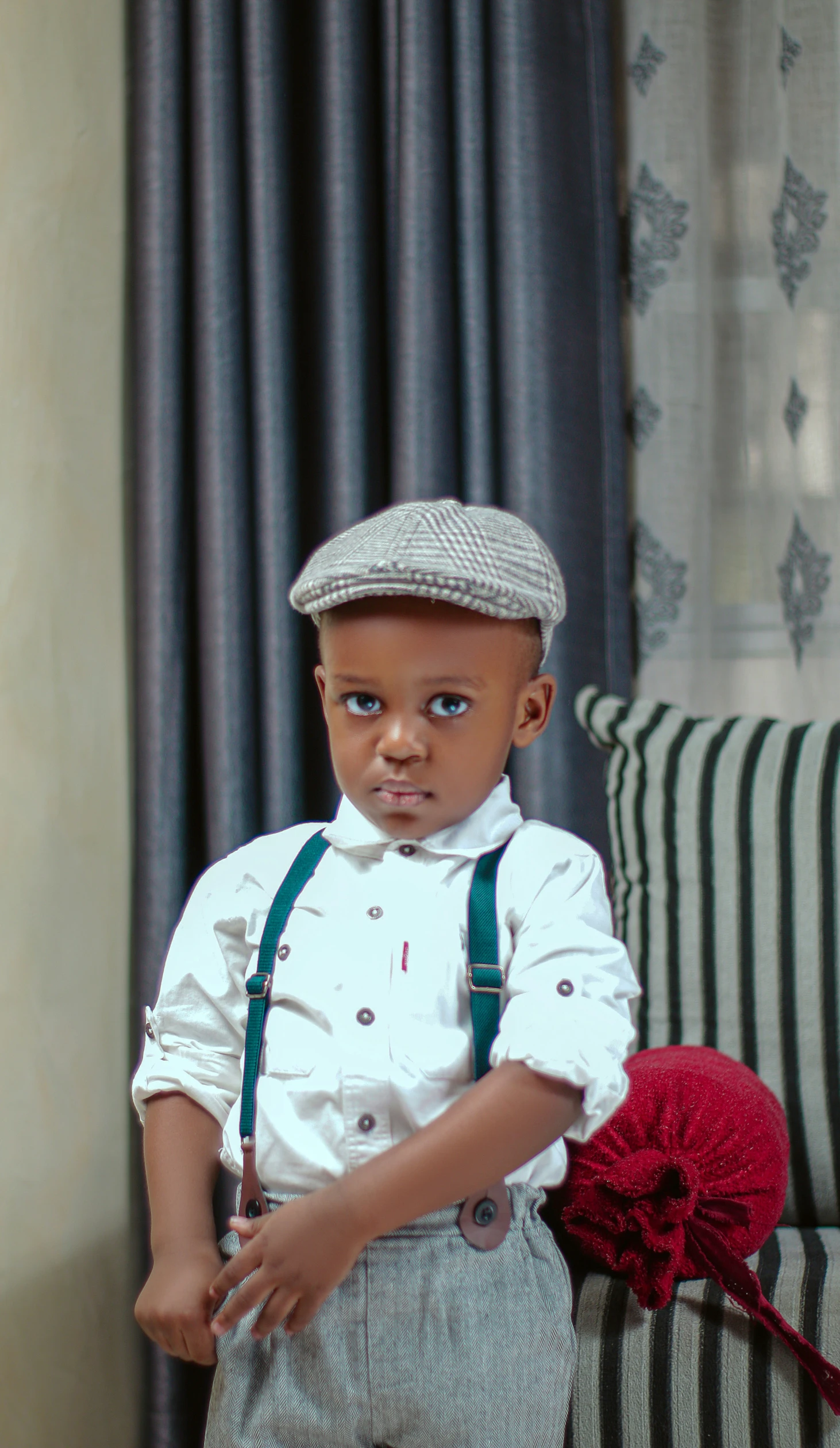 an adorable small boy in suspenders and a hat