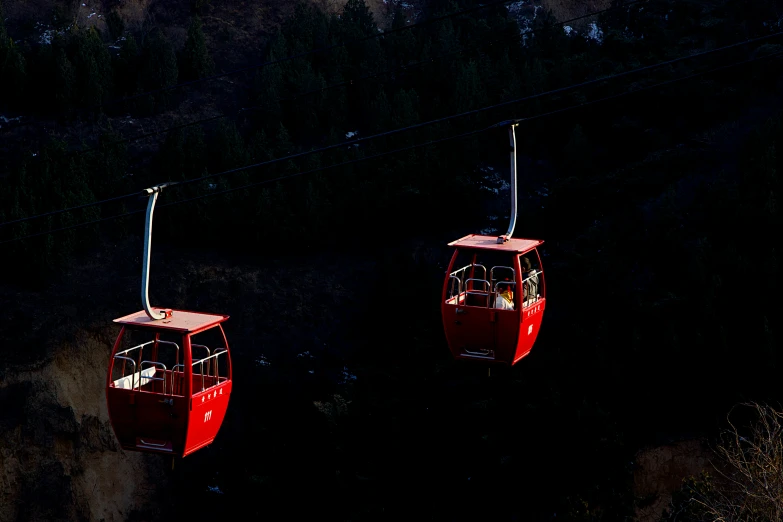 two red liftes with passengers on them in the dark