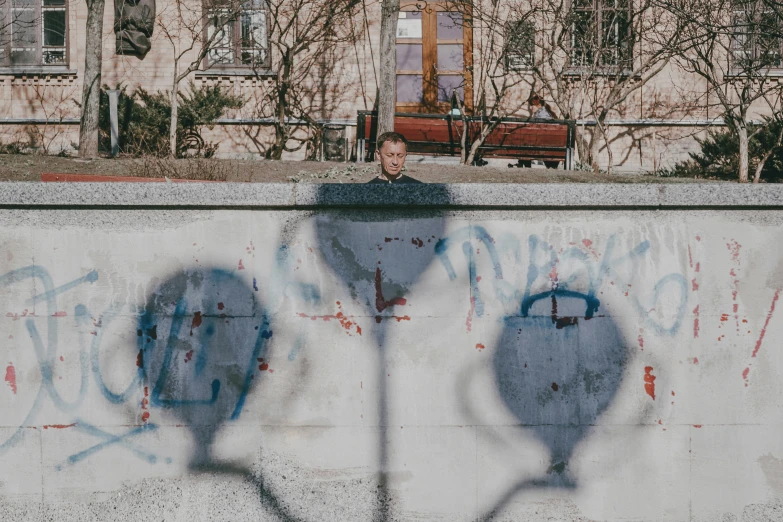 a person standing behind a wall with some graffitti on it