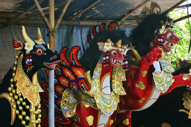 four colorful horses in costume displayed under a tent