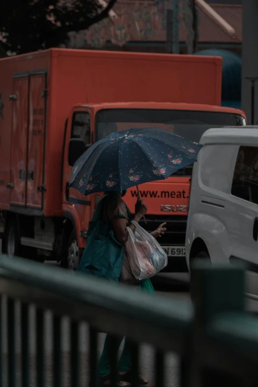 a woman with an umbrella is walking by parked trucks