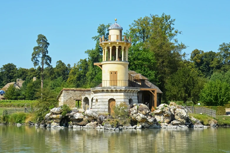a small tower sits above some water with greenery