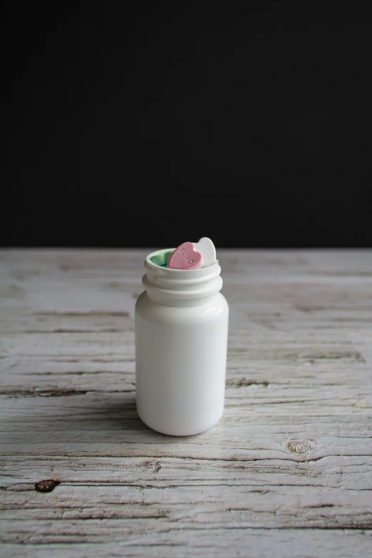 a white jar filled with candy on top of a wooden table
