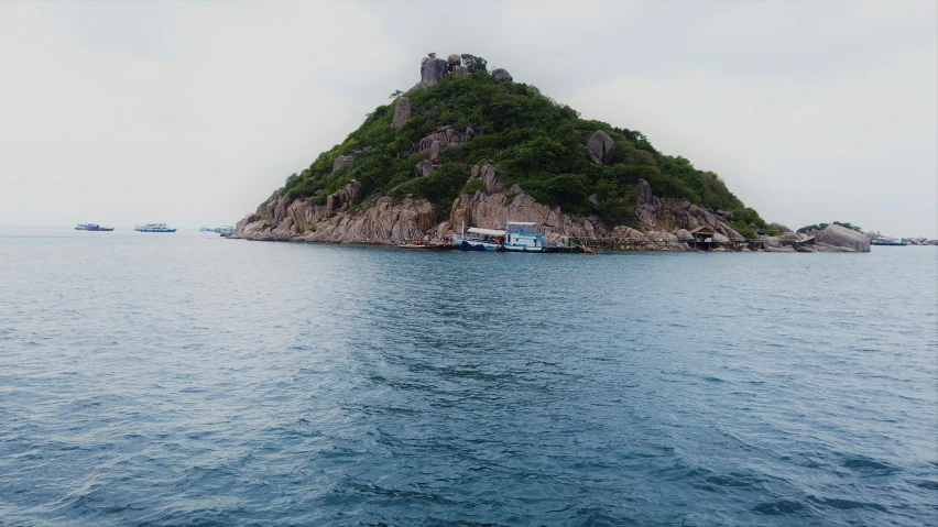 an island sits off the shore in front of several boats