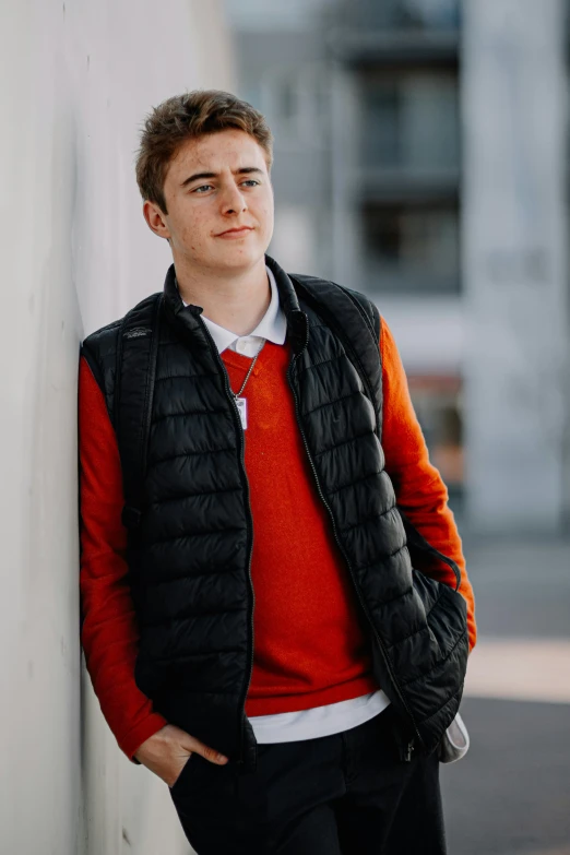 a young man poses against a white wall