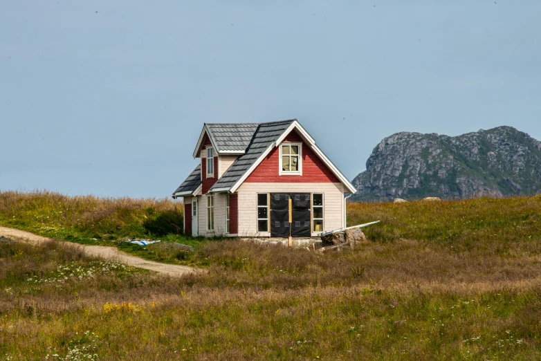 a house sitting on top of a hill with mountains behind it