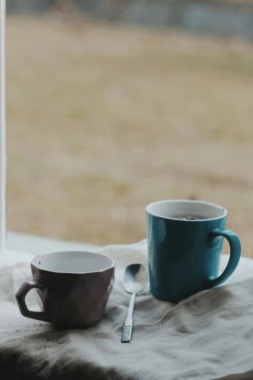 a couple of blue cups sitting next to a spoon