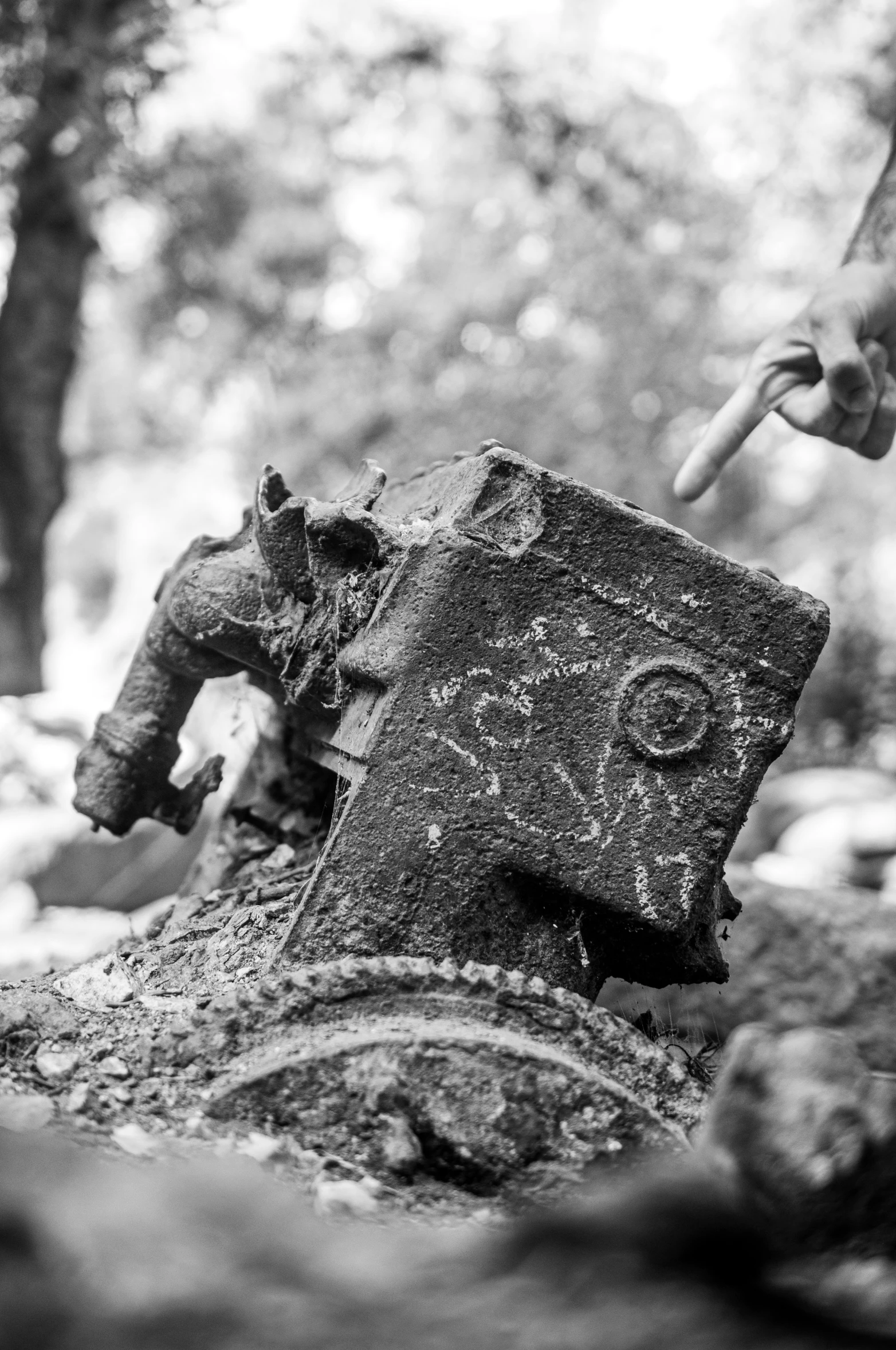 an old rusted stone head with hands reaching towards it