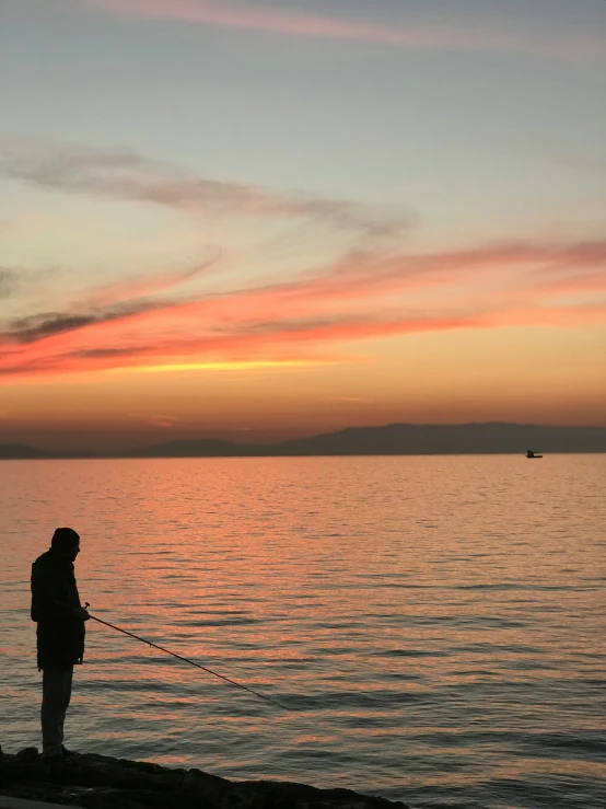 man standing near the water as the sun sets