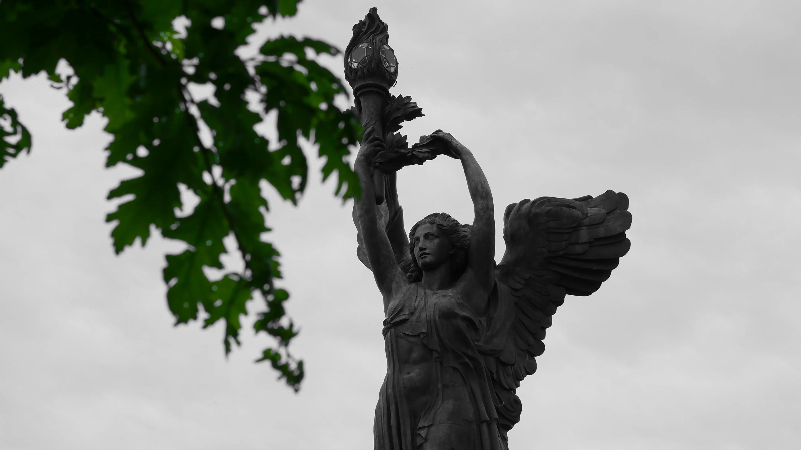 an angel sculpture with outstretched wings on a cloudy day