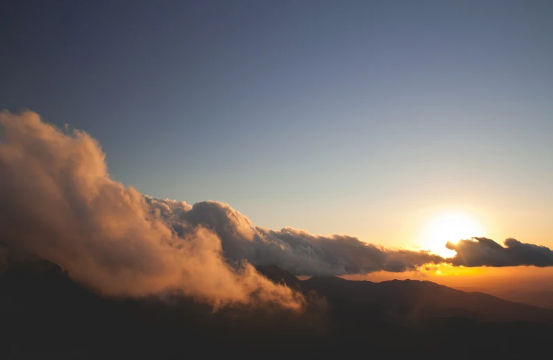 a cloud that is rising over some mountains