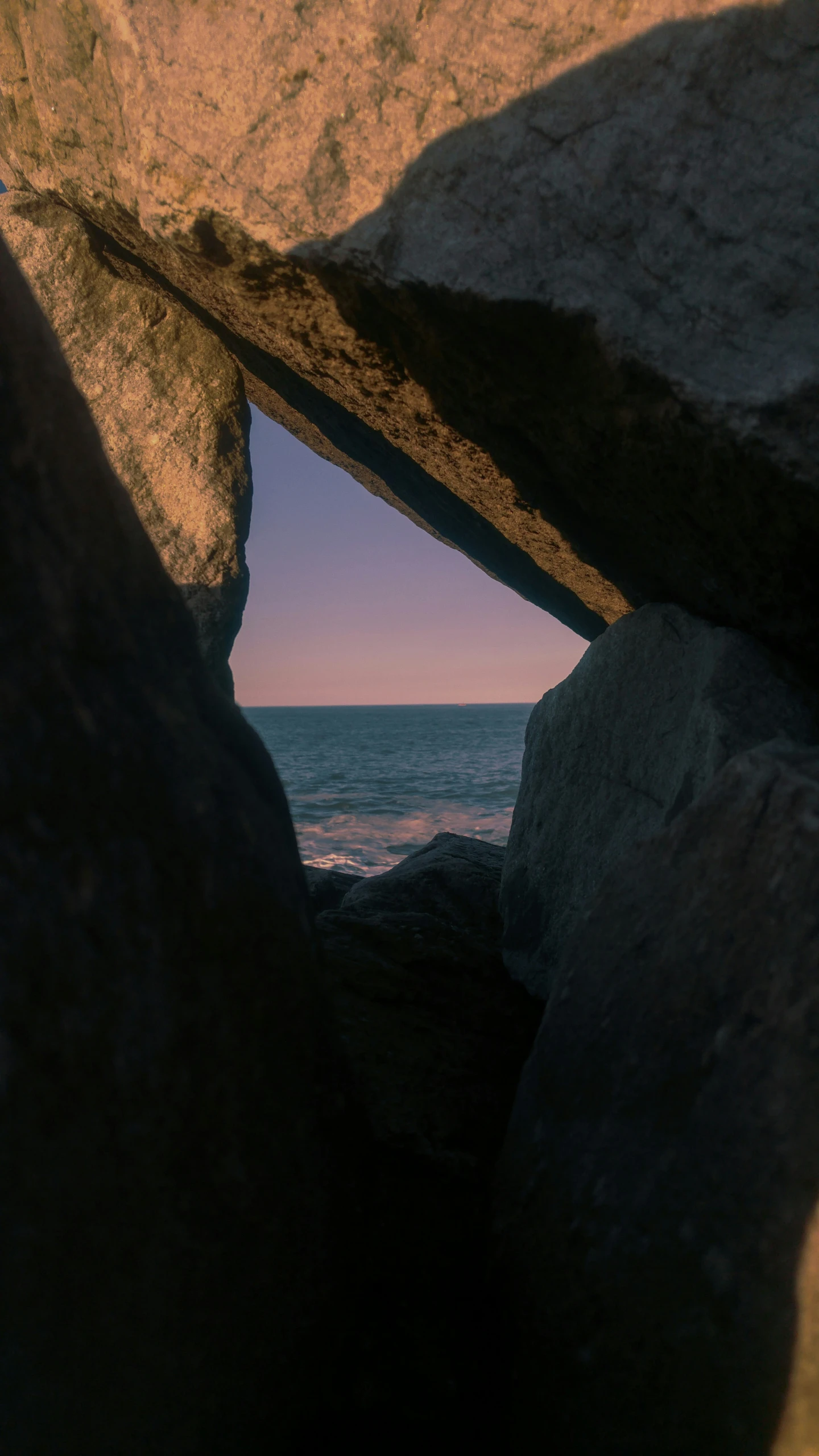 the ocean is seen through an opening in a rock