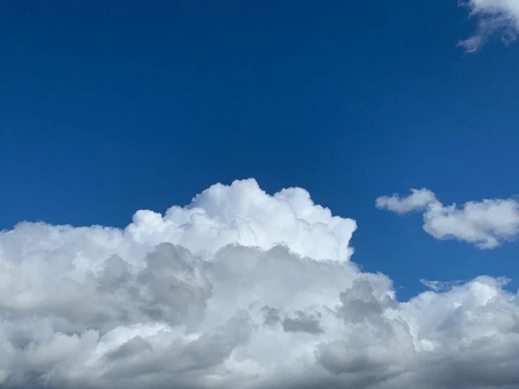 a jetliner flying over clouds under a blue sky