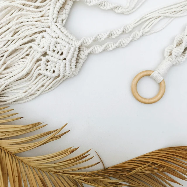 a white necklace with a ring sitting on top of palm leaves