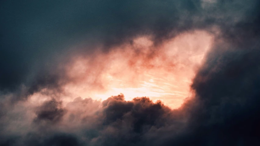 a cloudy sky and the sun peeking through clouds