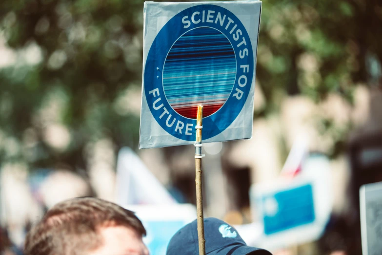 a person with a sign that reads scientist's future on it