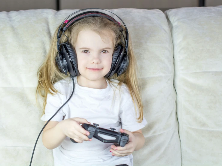 a girl laying on the couch wearing headphones and holding a controller