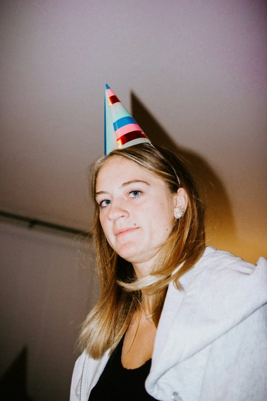 a woman wearing a birthday hat is smiling