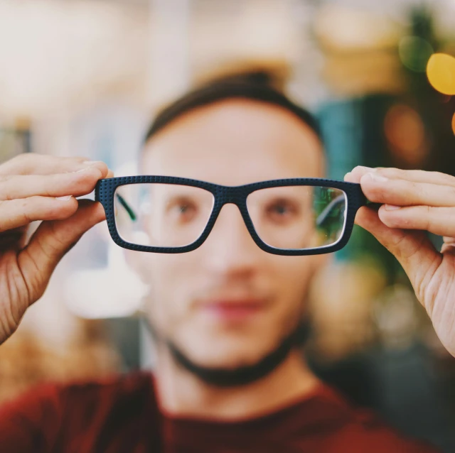 man in glasses looking through the glass to see inside