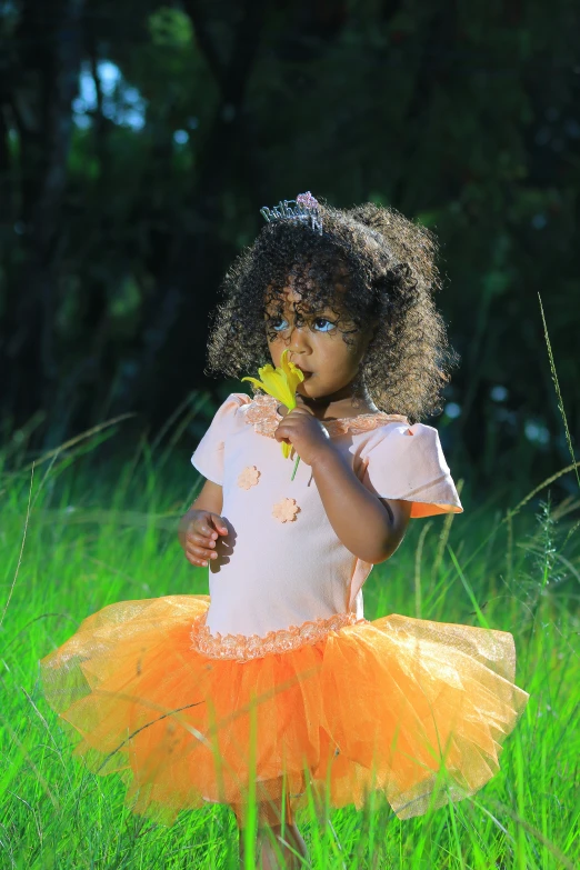 a little girl in a yellow skirt and orange dress holds a flower