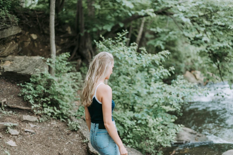 a woman in overalls is looking out at the river