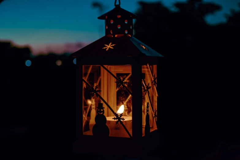 a lit candle in a light - up lantern in the dark