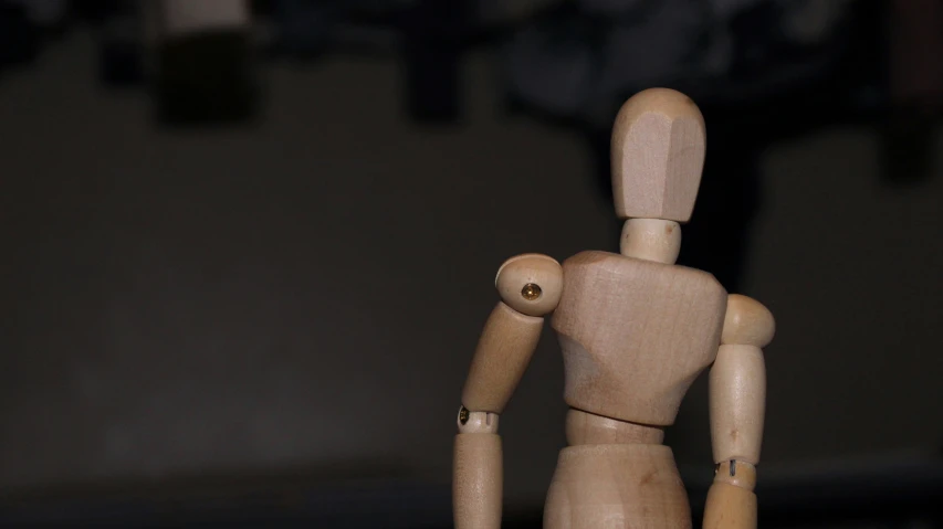 a doll with wooden face and body standing on a counter