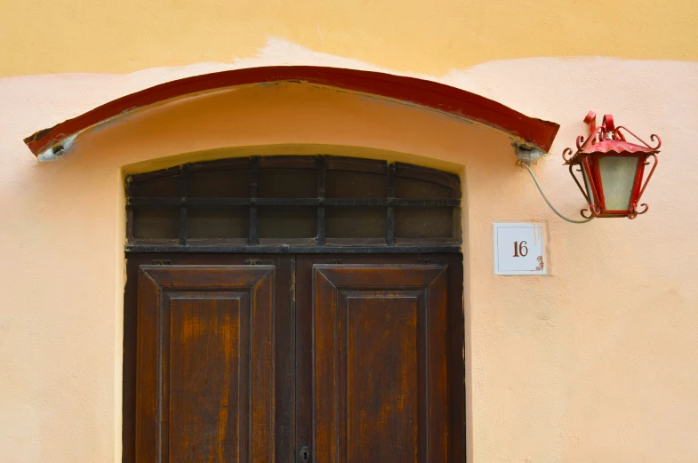 an open brown door with a lamp above it