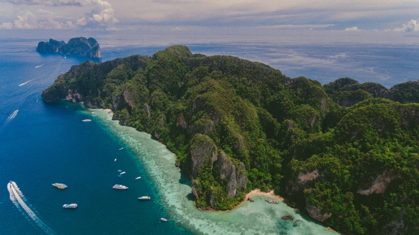 small boats traveling next to the shore and ocean