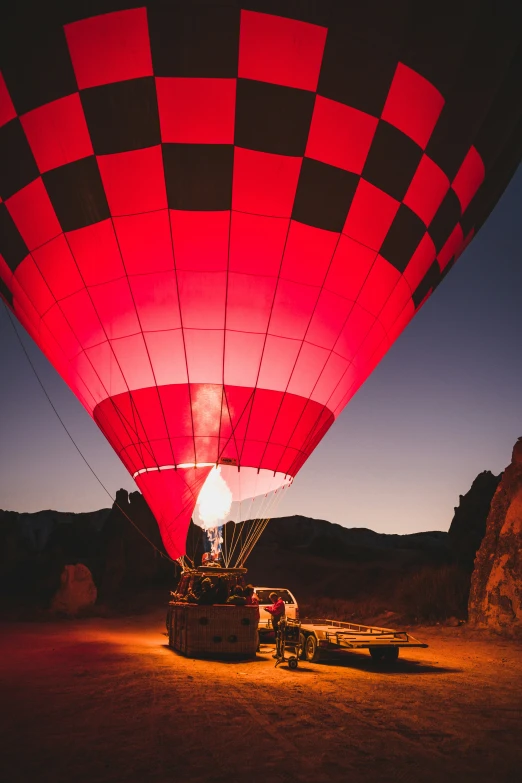 the lit up red  air balloon floats through the sky