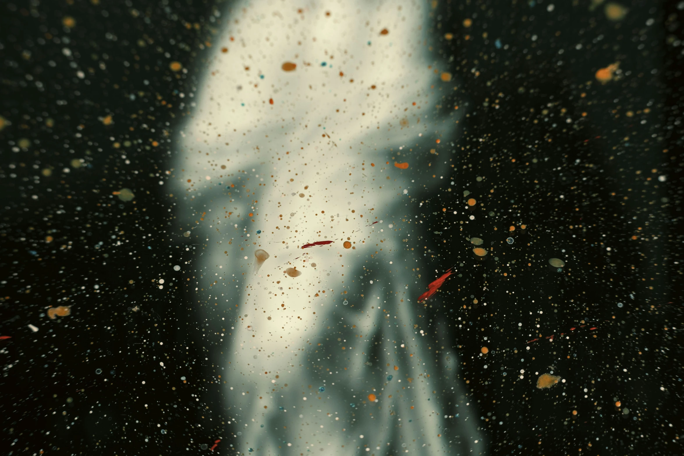 a rain soaked window shows the silhouette of a man