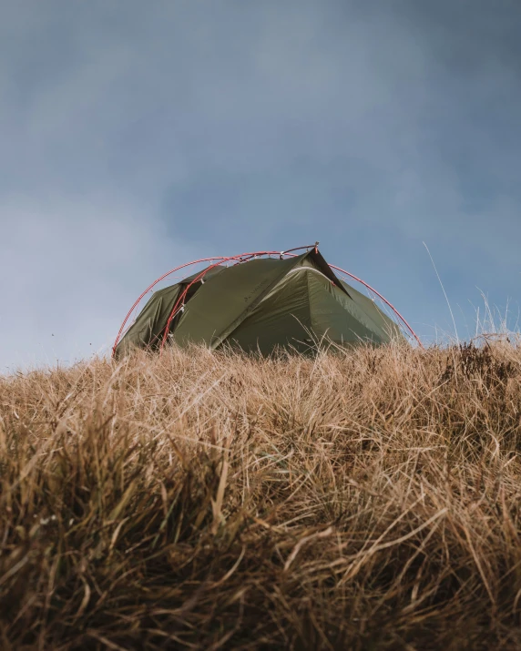 a tent pitched up on top of a grassy hill