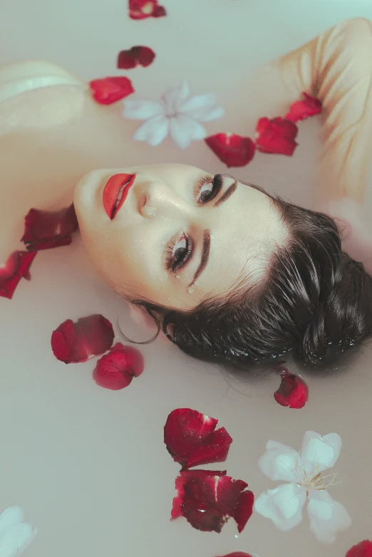 a woman laying on top of a bed of rose petals