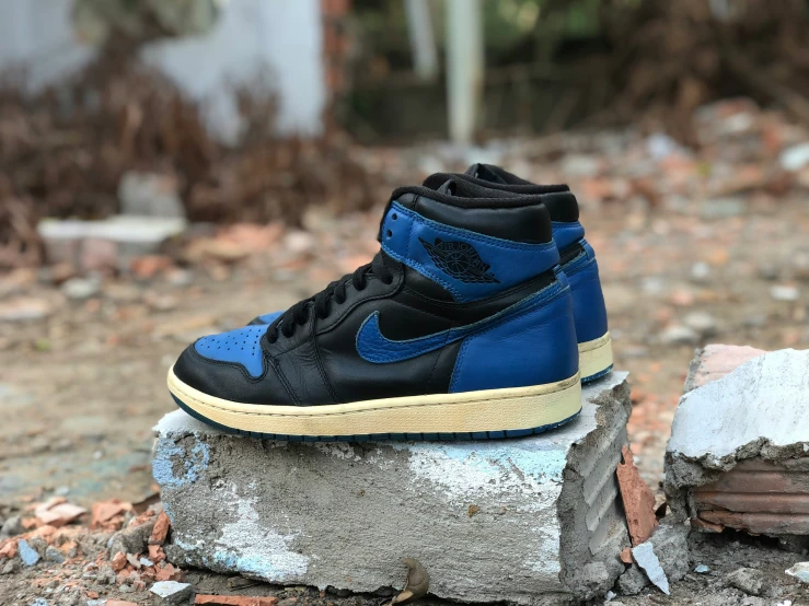 a blue and black jordan sneaker sits on top of a rock