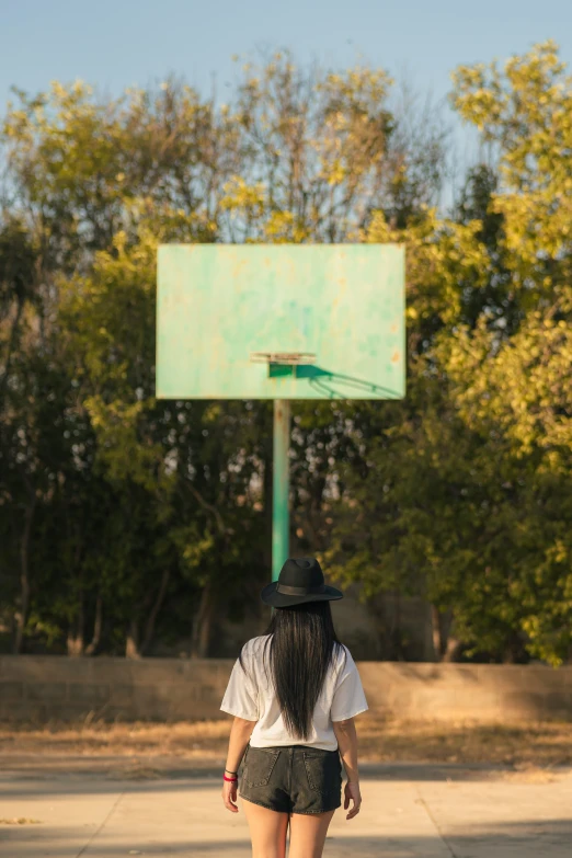 a woman with short black shorts and a hat standing in front of a basketball hoop