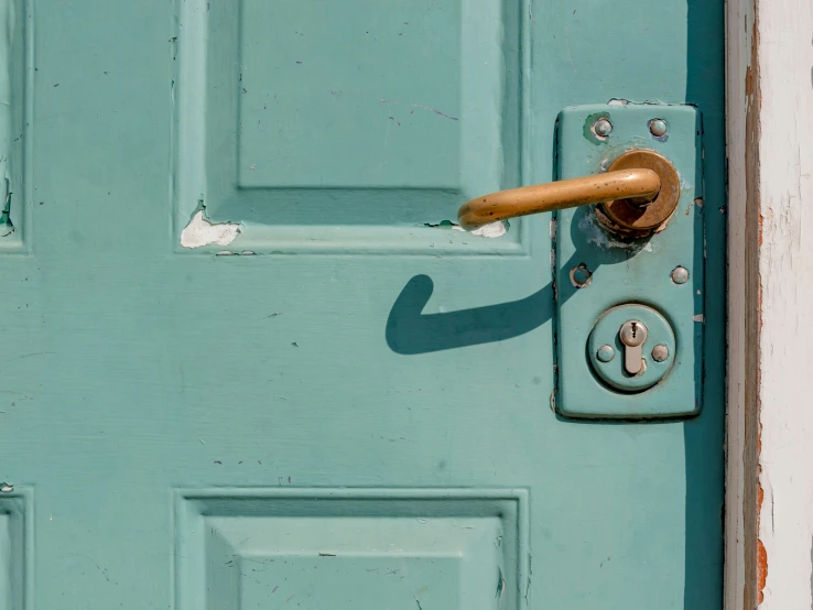 a rusted door handle on a teal wooden door