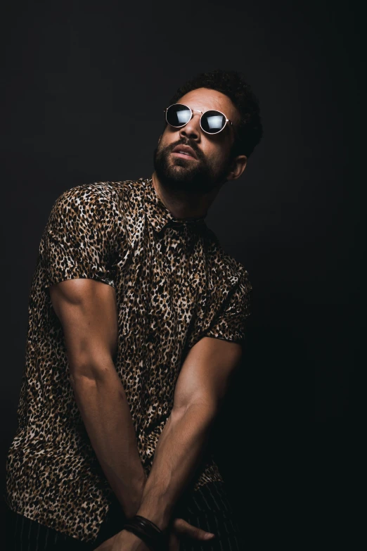 a bearded man in shades looking up while holding his hands on his lap