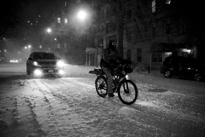 a man on his bicycle at night in the snow