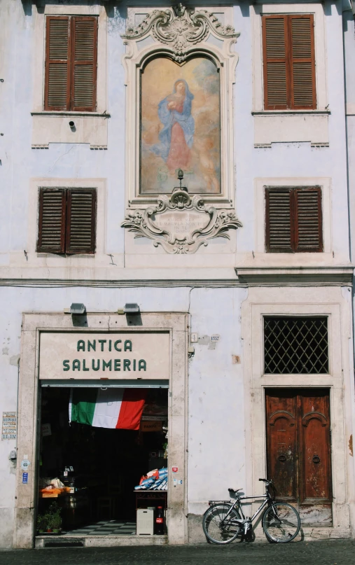 a white building with red shutters and a bicycle parked outside of it