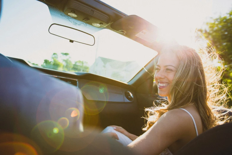 the sun shines brightly on a smiling woman as she sits in the back seat