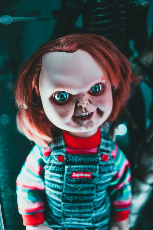 a creepy doll with big blue eyes sits on a shelf