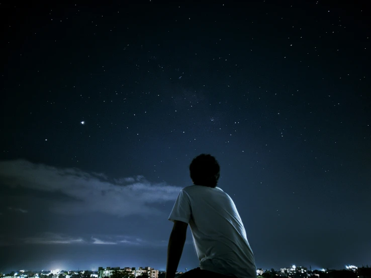 a man sitting on a wooden deck at night watching the stars