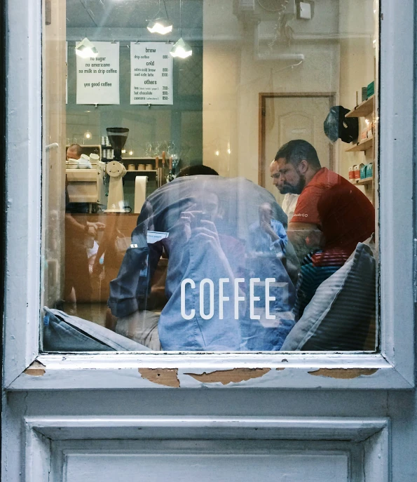 three people in window with the reflection of coffee and the pographer