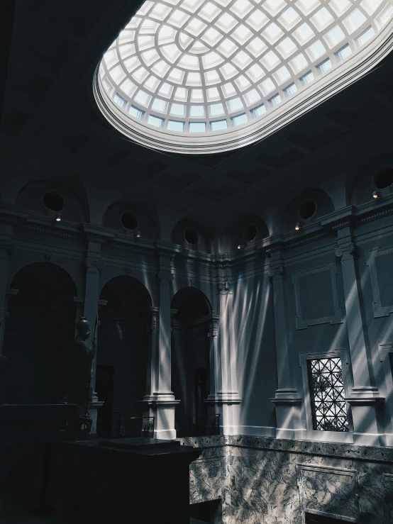 a ceiling with a big glass dome and some stone columns