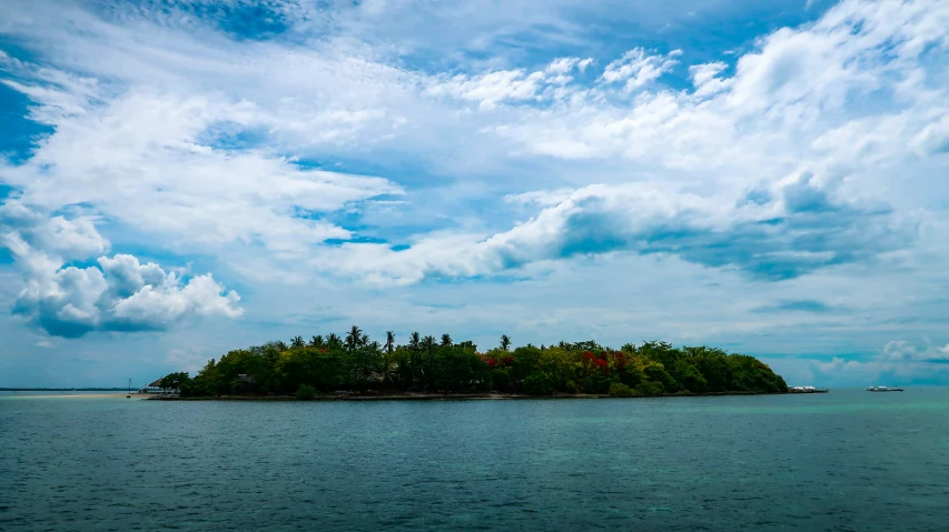 an island on the ocean under cloudy skies