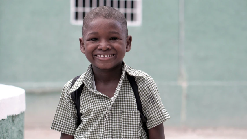 a small child with a backpack smiles at the camera