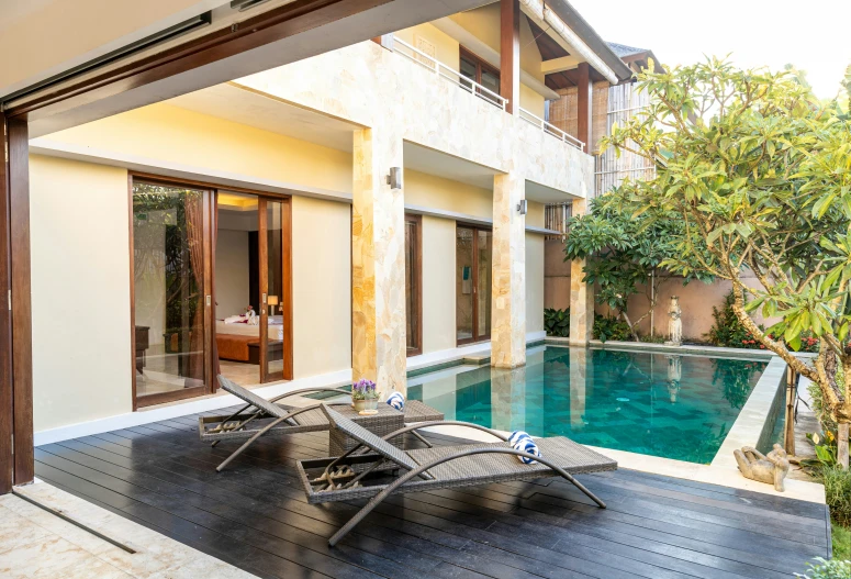 a pool with chairs next to it and a house