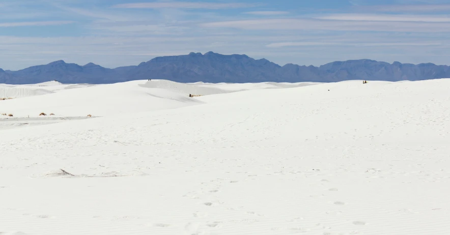 someone is hiking across a wide empty snowy field