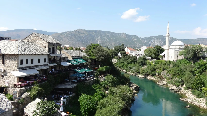 buildings and shops on side of river with hills behind