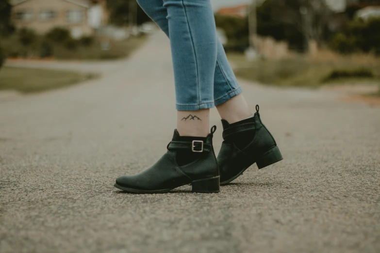 woman in black boots and jeans walking down street